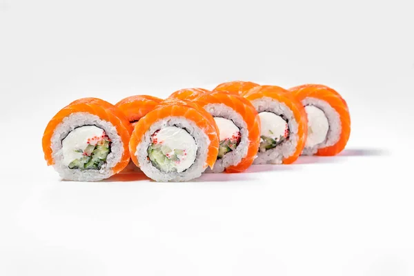 Roll Philadelphia with salmon. Sushi stuffed with Philadelphia cream cheese, cucumber, tobiko flying fish roe, wrapped in nori seaweed, rice and salmon sashimi. Sushi stands on a white background.