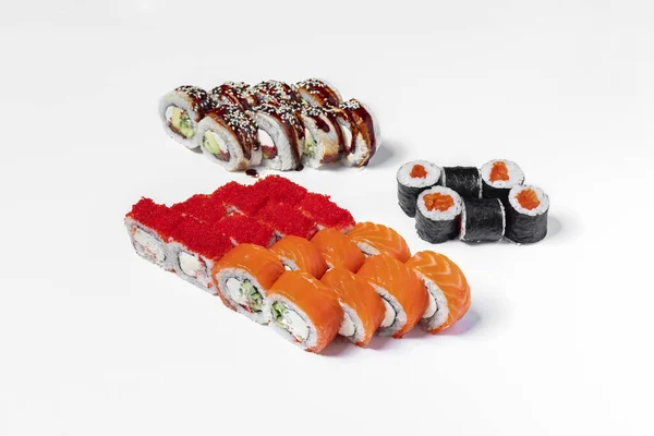 Philadelphia set and maki sushi. Four sushi rolls stand on a white background. Fmladelphia with salmon and tobiko caviar, Philadelphia with eel and tuna, California with Philadelphia cheese and shrimp and maki sushi with salmon.