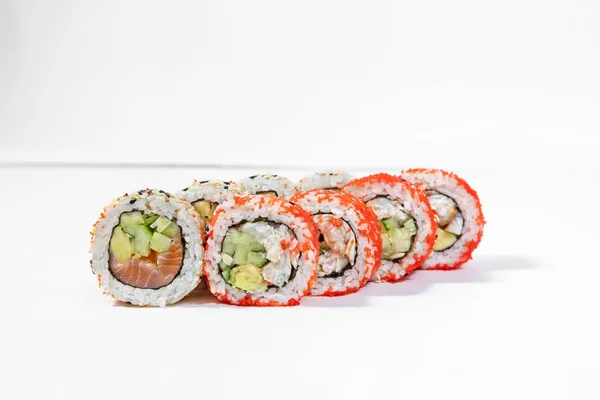 Sushi California mix. Mix roll of two types of California sushi. California with trout, avocado and cucumber in nori seaweed and sesame rice and California with eel, cucumber and tomu wrapped in rice with tobiko caviar. Roll stands on a white backgro