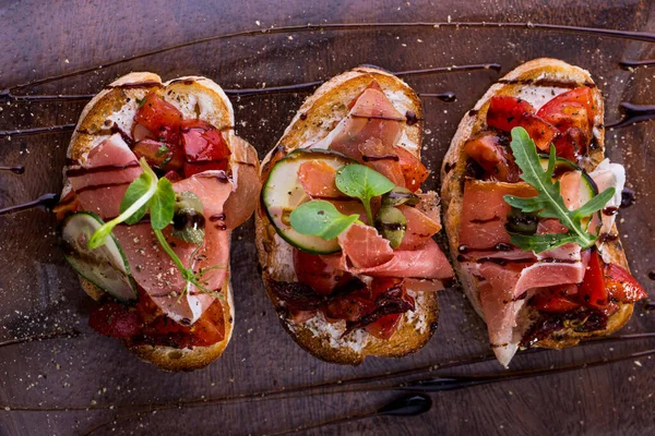 Tre Bruschetta Med Prosciutto Gurkskiva Mikrogröna Ärtor Och Soltorkade Tomater — Stockfoto