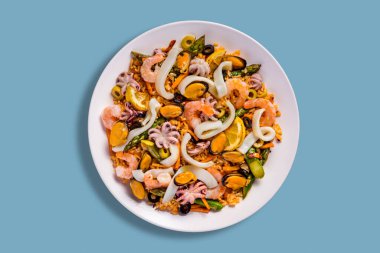 Mavi arkaplanda midye, ahtapot, kalamar halkaları, limon, karides, zeytin, pirinç, havuç ve fasulye ile salata.