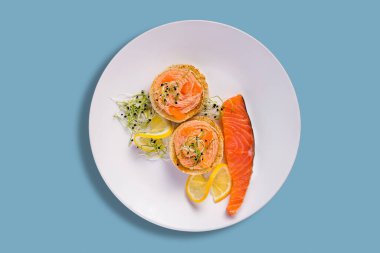 Somon filetosu, limon, lahana filizi ve havyar ezmeli sandviçler mavi arka planda.