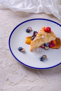 Napolyon pudra şekeri, yabanmersini, çilek, böğürtlen, ahududu ve karamel ile bir tabakta duruyor.