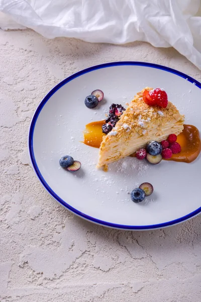 Napolyon pudra şekeri, yabanmersini, çilek, böğürtlen, ahududu ve karamel ile bir tabakta duruyor.