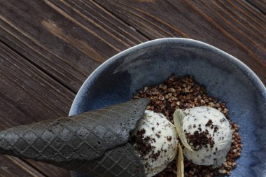 Waffle 'lı dondurma topları, ekmek kırıntıları ve mavi tabakta beyaz çikolata ve ahşap zemin