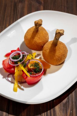 Tavuk budu domatesli, soğanlı, biberli ve maydanozlu ahşap bir arka planda.