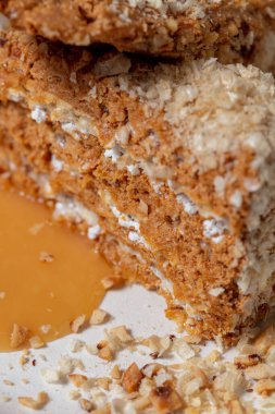 Ukrayna usulü, katmanlı waffle keki ve yoğunlaştırılmış süte batırılmış pastalar. Pastanın üstüne ezilmiş fındık serpiştirilmiş. Karamel sosu ve ezilmiş fındıklar pastanın altına saçılmış. Pasta beyaz, yuvarlak, seramik bir tabağın üzerinde duruyor. Tabak duruyor.