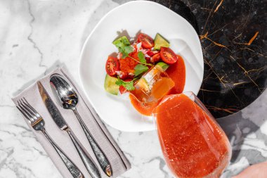 Kırmızı havyarlı gazpacho ve yengeç eti. Yengeç filetosu ve kırmızı havyarlı İtalyan domates çorbası. Yakınlarda büyük bir buz küpü var. Çorba hafif, seramik bir tabağa dökülüyor. Tabak aydınlık, mermer bir masa ve koyu mermer bir alanda duruyor.