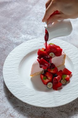 Çilekli reçelli cheesecake, yaban mersinli ve marşmelovlu bir tabakta