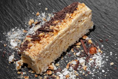 Kremalı Napolyon turtası, çikolata parçacıkları, fındık ve krema gri arka planda bir tabakta