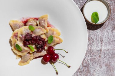 Kirazlı hamur tatlısı ve gri arka planda bir tabakta nane şekeri.