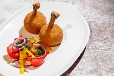 Tavuk budu domatesli, soğanlı, biberli ve maydanozlu gri bir arka planda.