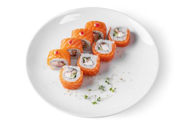 Roll with rice, salmon, eel, cucumber, avocado, mung bean salad, tobiko caviar, nori, sauce and Philadelphia cheese in a plate on a white background