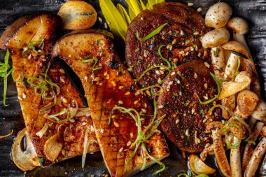 Assorted grilled Japanese mushrooms. Grilled Japanese mushrooms shiitaki, eringi, nameko are on the plate. Mushrooms lie on lemongrass leaves. Topped with unagi sauce, sprinkled with lime zest, pepper mixture and grilled garlic slices. Mushrooms lie 
