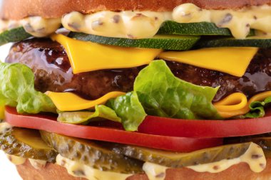 Köfteli hamburger, kabak, domates, sos, peynir, salatalık ve beyaz arka planda salata.