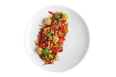 Spaghetti with red hazelnut sauce, breaded meat balls, chili, zucchini and parsley in a plate on a white plate