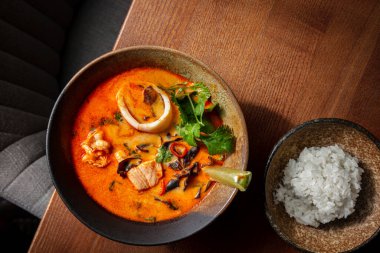 Squid meat with parsley, lime, chili, fish meat and red sauce in a plate on the table with rice in a plate