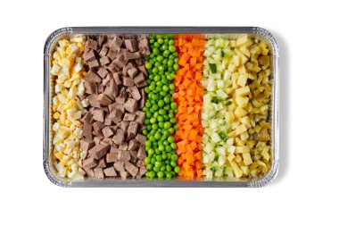 Kaynamış yumurta parçaları, domuz eti, bezelye, havuç, salatalık, patates, alüminyum kabartma tepsisinde salatalık turşusu.