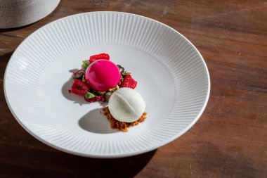 Ahududu aromalı şerbet ve ahududulu dondurma, nane, böğürtlen ve kızılcık ile ahşap bir masada.
