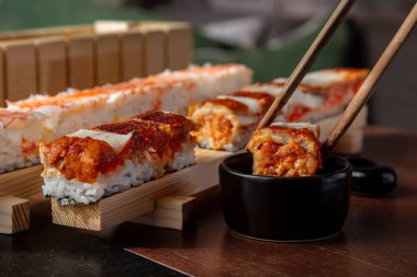 Pirinç, karides, yılan balığı, yuzo tobiko, tobiko havyar ve soslu rulo hazırlama. Yemek için sopa rolünü üstlenen bir adamla soslu ekmek yapmak için makinede.