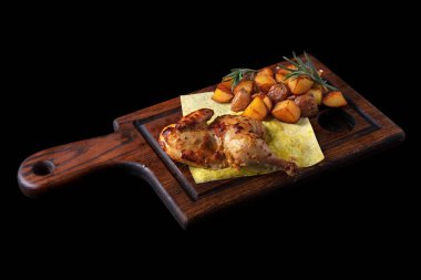 Yarım kızarmış tavuk, kızarmış patates, biberiye ve siyah arka planda tahtanın üzerinde pide ekmeği.