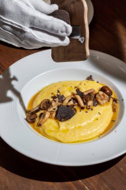 Mashed potatoes with mushrooms and grated truffle in a plate on the table