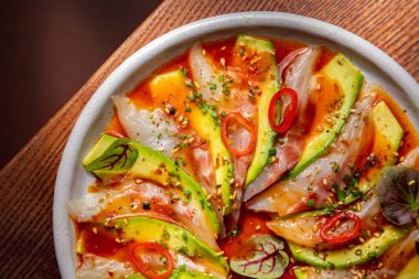 Mürekkep balığı etli saşimi, avokado, ahtapot, susam tohumu, biber, lahanalar ve mermer tabakta mastürbasyon yaprakları.