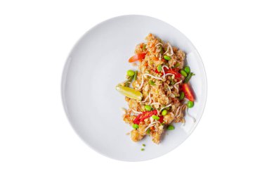 Rice with shrimps, chili beans, lemon, sprouted sprouts, tomatoes and peanuts in a plate on a white plate