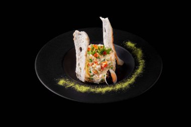 Havuçlu Olivier salatası, bezelye, patates, et, roka, somon havyarı, siyah arka planda kaynamış yumurta ve ekmek.