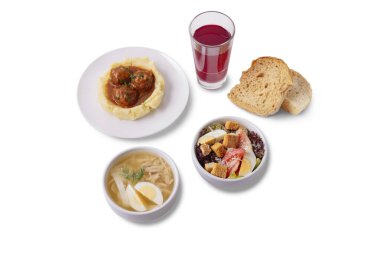 Karmaşık bir yemek. Kaynamış yumurta, spagetti ve et ile bir tabakta köfte soslu patates püresi haşlanmış yumurta, kızarmış yumurta, kızarmış ekmek, domates, marul, ekmek ve beyaz arka planda duran bir bardakta komposto.