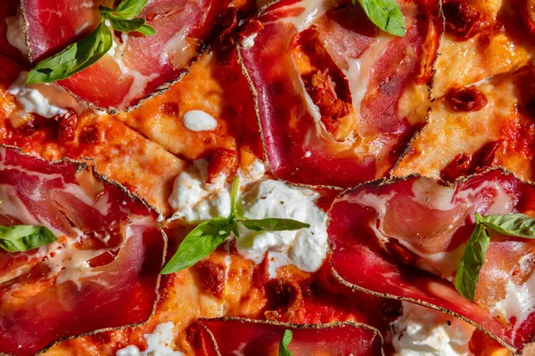 Pizza with prosciutto, cheese, sauce, basil and ketchup close-up