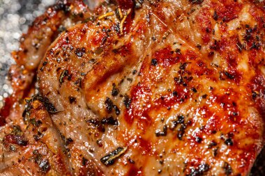 Bir parça dana eti. Kemikte üç parça dana eti var, ızgarada. Parçalar birbirinin üstünde, yanında marul ve kırmızı soğan halkalarından bir yaprak uzanıyor. Kare gümüş, yuvarlak bir tabakta yatıyor. Tabak bir ışıkta duruyor, keten arka plan..