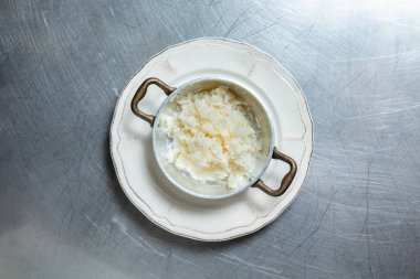 Pembe arka planda bir tabakta haşlanmış pirinç.