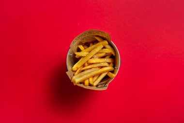 Fried fries with salt in a small bucket on a red background