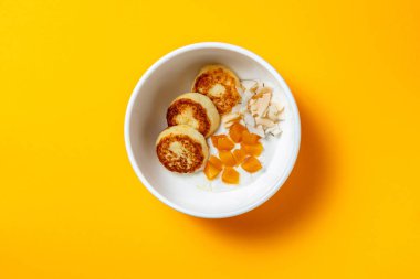 Şeftalili ve hindistan cevizli peynirli kekler sarı arka planda bir kasede.