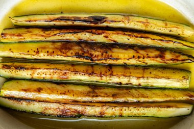 Yeşil arka planda oval bir tabakta tereyağı ve şarapla kızarmış kabak.