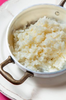 Pembe arka planda bir tabakta haşlanmış pirinç.