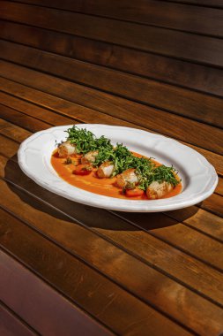 Ton balığıyla doldurulmuş mürekkep balığı ve kızarmış balık. Üstte parey var, şeritler halinde kesilmiş. Mürekkep balığı oval seramik bir tabakta, üzerine mango-chili sosu dökülüyor. Tabak, tahtanın kahverengi arka planında duruyor..