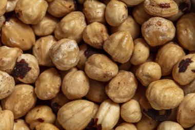 Kabuksuz ve kabuksuz kavrulmuş fındık. Cevizler ışıkta yatar, seramik kase. Kase bir ışığın üzerinde duruyor, keten masa örtüsü..