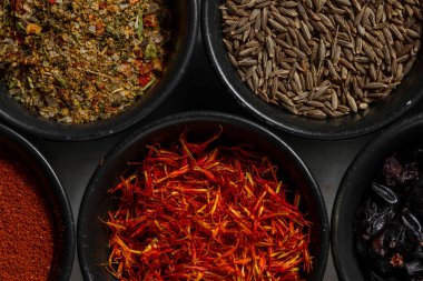 Kâselerdeki çeşitli Gürcü baharatları. safran, Svan tuzu, zıpzıp, karanfil, kuru üzüm, tüm baharatlar ve diğerleri. Baharatlar siyah, yuvarlak, seramik kaselerde yatar. Kâseler ışığın üzerinde duruyor, keten masa örtüsü..