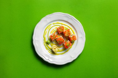 Somon, Japon mayonezi ve avokado ile doldurulmuş tobiko rulo, pirinç ve tobiko havyarla sarılmış. Üstü yeşil soğan ve limon aromalı. Yuvarlak, hafif, seramik bir tabakta kalıplı. Sos bir tabağa bulaşmış ve salamura edilmiş. 