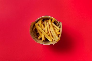 Fried fries with salt in a small bucket on a red background