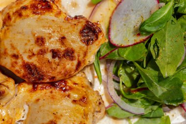 Chicken kebab. Four pieces of chicken kebab on a sheet of thin Armenian lavash with a mix of greens and radish salad. The food lies on a ceramic plate, on a light tablecloth.