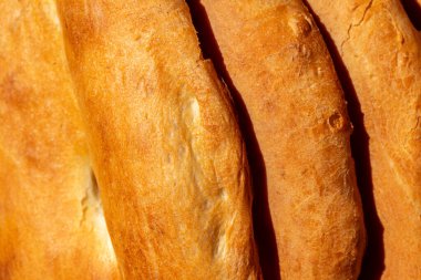 Georgian Shoti bread baked in a tandoor oven until golden brown lies on a round ceramic plate against a background of ceramic tiles.