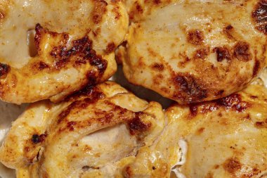 Chicken kebab. Four pieces of chicken kebab on a sheet of thin Armenian lavash with a mix of greens and radish salad. The food lies on a ceramic plate, on a light tablecloth.