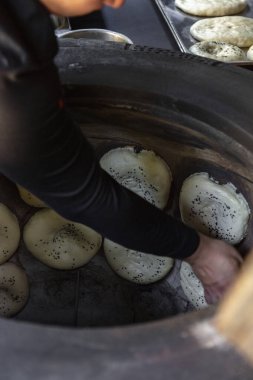 In a large tandoor oven, various Caucasian breads are laid out along the walls for baking.
