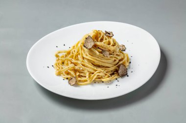 Hafif seramik tabakta mantar dilimli ev yapımı spagetti makarna gri arka planda duruyor..