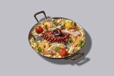 Ahtapot, levrek, mürekkep balığı ve sata soslu kiraz domatesli bir makarna. Yiyecekler gri arka planda sapları olan metal bir kasede yatıyor..