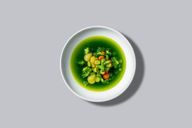 Brokoli, havuç ve patatesli sebze çorbası. Gri bir zemin üzerinde seramik tabakta..