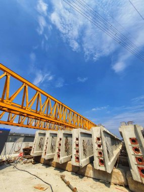 Several girders are arranged in the stockyard for the preparation of erection concrete precast girders using a yellow gantry launcher.